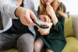 couple holding remote and eating popcorn