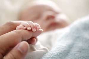 Newborn baby hand holding adult's fiinger