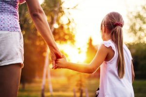 Woman holding child's hand outdoors